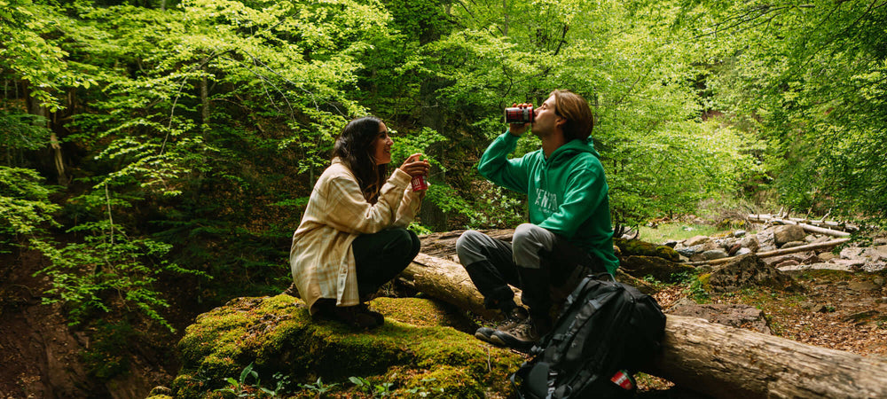 Aventura Self Heating Beverages and Self Heating Soups being enjoyed while 2 people are resting in a forest while on a hike