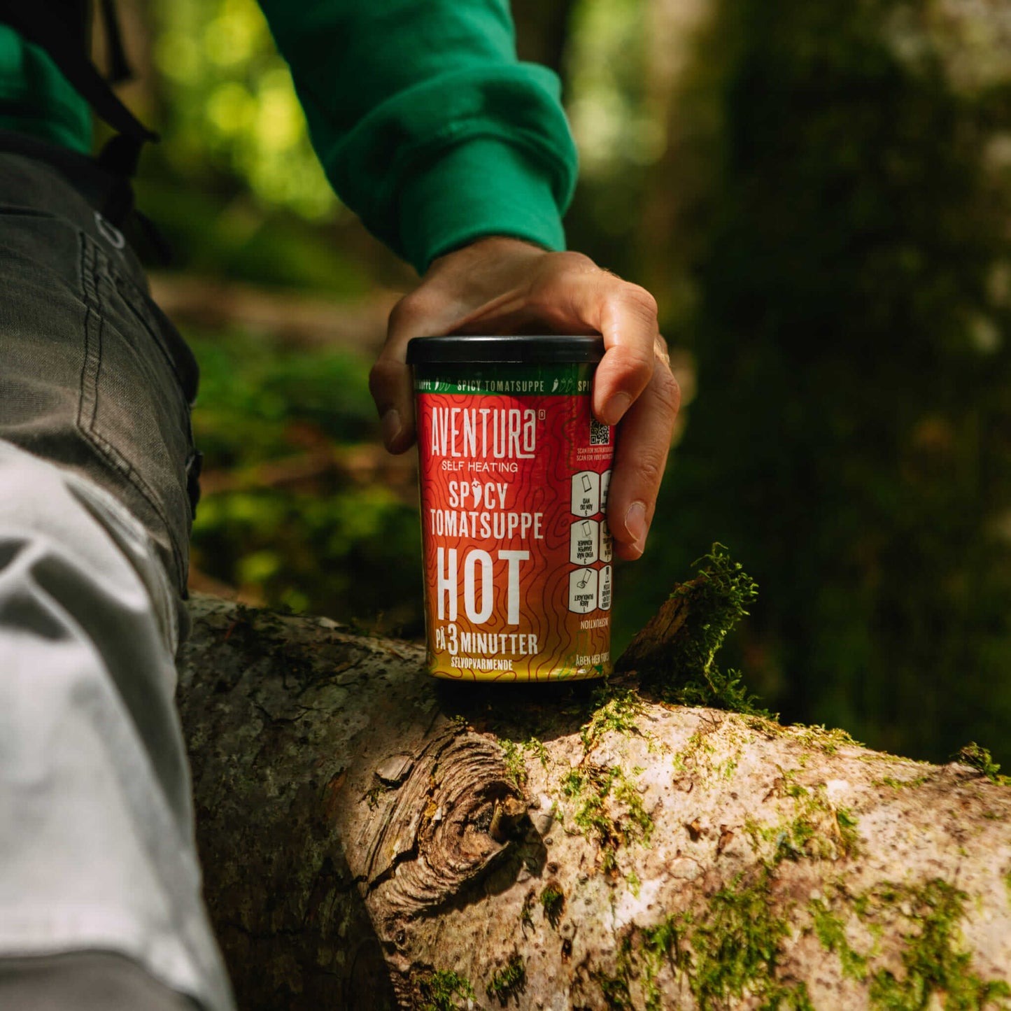 Aventura Self Heating Spicy Tomato Soup Hot in 3 minutes being placed down on a log in a forest held by a person